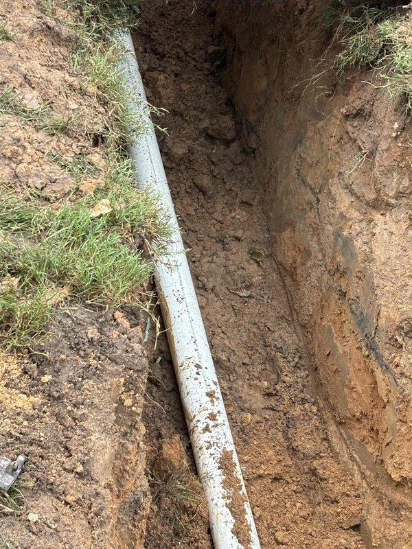 Completed full sewer and water line replacement at residential property. Excavated trench approximately 2-3 feet deep through clay-based soil to access existing utility lines. Removed old piping and installed new white PVC water supply line and sewer drain lines with proper fittings and connections. Verified proper depth and grade for drainage using measuring equipment. All new plumbing connections were assembled and tested at junction points. Excavation work included careful trenching to preserve surrounding lawn areas where possible, with clean vertical trench walls maintained throughout the installation process. Completed full sewer and water line replacement at residential property. Excavated trench approximately 2-3 feet deep through clay-based soil to access existing utility lines. Removed old piping and installed new white PVC water supply line and sewer drain lines with proper fittings and connections. Verified proper depth and grade for drainage using measuring equipment. All new plumbing connections were assembled and tested at junction points. Excavation work included careful trenching to preserve surrounding lawn areas where possible, with clean vertical trench walls maintained throughout the installation process.