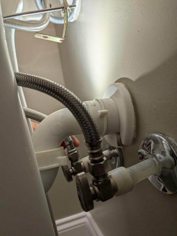# Leak Repair - Under Sink Plumbing

Responded to report of leak beneath bathroom sink. Upon inspection, identified leak originating from connections between flexible braided water supply lines and shut-off valve assembly. Found loose compression fittings at multiple connection points where metallic braided hoses interface with PVC fittings and wall-mounted shut-off valve.

Tightened compression nuts on both hot and cold water supply lines using appropriate wrench. Inspected all visible plumbing connections including flexible supply lines, shut-off valve with black handle, and metal clamps securing lines to cabinet structure. Verified integrity of braided stainless steel hoses and black rubber supply line. Tested all connections for proper seal by running water and monitoring for moisture. Confirmed leak resolved with no active dripping from fittings or valve connections. All plumbing components returned to normal operating condition.