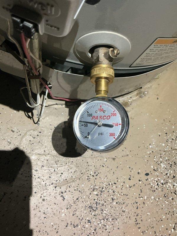Responded to kitchen sink garbage disposal leak affecting basement area. Upon inspection, found jammed disposal unit causing water intrusion to lower level. Cleared disposal jam and assessed leak source. Verified water heater pressure readings within normal operating range using existing gauge during basement inspection. Additionally addressed loose shower handle hardware requiring adjustment. Documented existing floor conditions in affected basement area showing water damage to flooring transition between vinyl planking and concrete subfloor. Recommended monitoring for additional moisture issues and potential flooring repair in impacted zone.