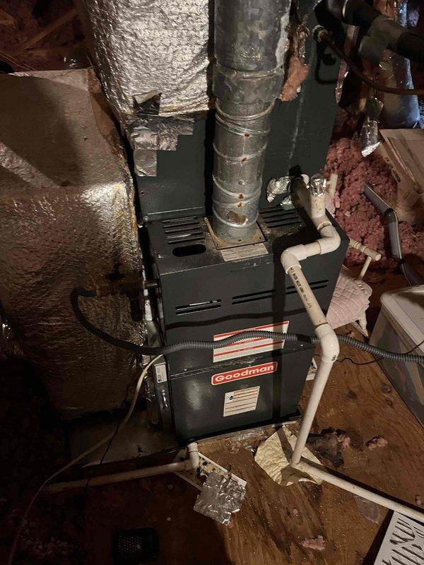 Responded to two HVAC service calls in the same area. First call addressed water accumulation in the drain pan, inspected condensate drainage system including white PVC drain lines and verified proper flow. Second call was a no cooling complaint, performed diagnostic inspection of Goodman air handler unit installed in attic space. Examined unit operation, ductwork connections, and overall system condition. Documented existing installation showing vertical supply duct with reflective foil insulation, multiple horizontal branch ducts with deteriorated insulation wrap exposing underlying pink fiberglass material, and condensate drain routing. Noted signs of normal wear on duct insulation with tears and frayed edges throughout the attic installation. Inspected electrical connections via black flexible conduit and verified unit mounting on wooden platform. Both systems evaluated for proper operation and drainage functionality. Responded to two HVAC service calls in the same area. First call addressed water accumulation in the drain pan, inspected condensate drainage system including white PVC drain lines and verified proper flow. Second call was a no cooling complaint, performed diagnostic inspection of Goodman air handler unit installed in attic space. Examined unit operation, ductwork connections, and overall system condition. Documented existing installation showing vertical supply duct with reflective foil insulation, multiple horizontal branch ducts with deteriorated insulation wrap exposing underlying pink fiberglass material, and condensate drain routing. Noted signs of normal wear on duct insulation with tears and frayed edges throughout the attic installation. Inspected electrical connections via black flexible conduit and verified unit mounting on wooden platform. Both systems evaluated for proper operation and drainage functionality.