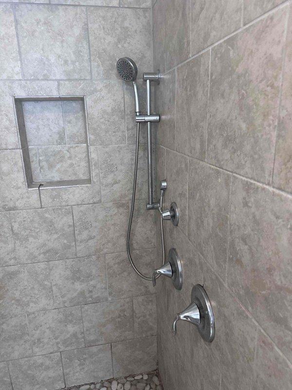 Responded to report of two non-functioning sinks in bathroom. Upon inspection, determined the issue was related to the shower fixture system rather than separate sink fixtures. Evaluated the chrome shower control valves and tub spout assembly mounted on the tiled wall. Assessed water flow and pressure through both the overhead rainfall showerhead and handheld shower unit on the slide bar. Tested all control mechanisms to verify proper operation and restored full functionality to the shower system. Responded to report of two non-functioning sinks in bathroom. Upon inspection, determined the issue was related to the shower fixture system rather than separate sink fixtures. Evaluated the chrome shower control valves and tub spout assembly mounted on the tiled wall. Assessed water flow and pressure through both the overhead rainfall showerhead and handheld shower unit on the slide bar. Tested all control mechanisms to verify proper operation and restored full functionality to the shower system.
