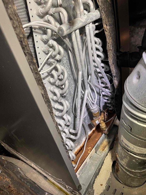 Responded to service call for HVAC system with active leak from main drain line. Upon inspection of attic-installed Lennox furnace unit, confirmed previous repair attempt was unsuccessful and leak persisted from within the unit. Examined white plastic condensate drain assembly and evaporator coil system to identify source of water discharge. Photographed installation showing ductwork configuration, refrigerant lines, and coil assembly with visible dust accumulation on aluminum fins. Documented condition of condensate drainage components and internal coil housing to determine appropriate repair solution for ongoing water leak issue. Responded to service call for HVAC system with active leak from main drain line. Upon inspection of attic-installed Lennox furnace unit, confirmed previous repair attempt was unsuccessful and leak persisted from within the unit. Examined white plastic condensate drain assembly and evaporator coil system to identify source of water discharge. Photographed installation showing ductwork configuration, refrigerant lines, and coil assembly with visible dust accumulation on aluminum fins. Documented condition of condensate drainage components and internal coil housing to determine appropriate repair solution for ongoing water leak issue.