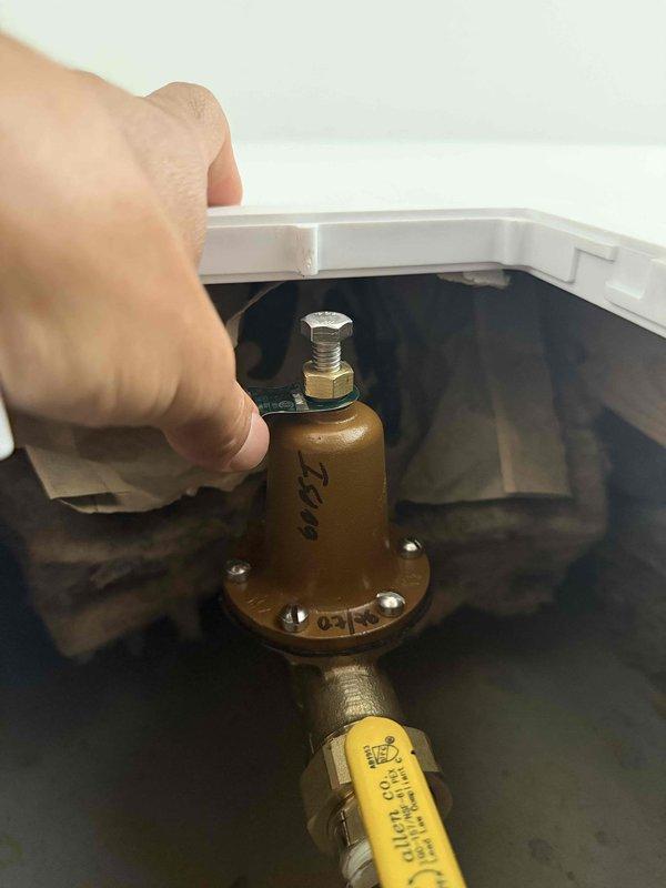 Inspected and serviced pressure relief valve (PRV) on water heating system. Accessed equipment through wall-mounted panel, verified proper valve operation, and confirmed secure mounting within drain pan. All components functioning within normal parameters upon completion.