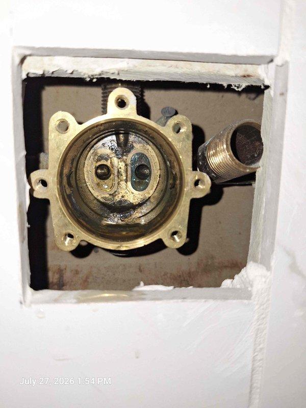 Responded to plumbing issue where back main shower was not receiving cold water and front shower was not receiving hot water. Upon inspection, accessed wall cavities at both shower locations to examine valve assemblies and supply line connections. Identified crossed or improperly connected hot and cold water supply lines serving the two shower fixtures. Documented existing plumbing configuration showing white plastic threaded connectors, brass valve bodies, and supply piping within wall openings. Traced water supply lines to determine correct routing for proper hot and cold water delivery to each shower location. Issue resolved by correcting the supply line connections to restore proper hot and cold water flow to both showers. Responded to plumbing issue where back main shower was not receiving cold water and front shower was not receiving hot water. Upon inspection, accessed wall cavities at both shower locations to examine valve assemblies and supply line connections. Identified crossed or improperly connected hot and cold water supply lines serving the two shower fixtures. Documented existing plumbing configuration showing white plastic threaded connectors, brass valve bodies, and supply piping within wall openings. Traced water supply lines to determine correct routing for proper hot and cold water delivery to each shower location. Issue resolved by correcting the supply line connections to restore proper hot and cold water flow to both showers.