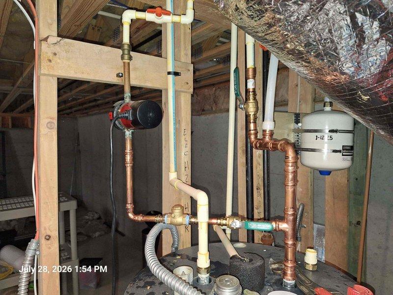 Responded to service call for non-operational water heater system. Upon inspection, identified issues with the hydronic heating system's expansion tank and pressure regulation components. Installed new thermal expansion tank with proper copper piping connections and brass valve assemblies to prevent excessive pressure buildup in the closed-loop system. Configured pressure relief valving with color-coded temperature and pressure controls to maintain safe operating parameters between acceptable PSI ranges. Integrated circulation pump assembly with PVC and copper piping network, ensuring proper flow throughout the distribution system. Verified all connections for leaks, tested pressure gauge readings to confirm system operating within manufacturer specifications, and confirmed proper expansion tank pre-charge pressure. System restored to full operational status with all safety devices functioning correctly. Responded to service call for non-operational water heater system. Upon inspection, identified issues with the hydronic heating system's expansion tank and pressure regulation components. Installed new thermal expansion tank with proper copper piping connections and brass valve assemblies to prevent excessive pressure buildup in the closed-loop system. Configured pressure relief valving with color-coded temperature and pressure controls to maintain safe operating parameters between acceptable PSI ranges. Integrated circulation pump assembly with PVC and copper piping network, ensuring proper flow throughout the distribution system. Verified all connections for leaks, tested pressure gauge readings to confirm system operating within manufacturer specifications, and confirmed proper expansion tank pre-charge pressure. System restored to full operational status with all safety devices functioning correctly.