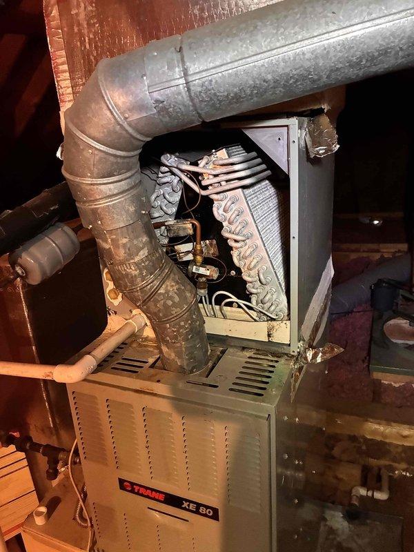 Responded to service call for HVAC system leaking in attic space. Upon inspection, identified active leak at evaporator coil assembly located within Trane XE 80 furnace unit. Opened top access panel and examined A-coil configuration, checking for clogged condensate drain line, damaged drain pan, and coil freeze conditions. Inspected condensate drainage system including PVC piping and verified proper pitch and flow. Documented equipment condition and leak source with photographs showing furnace interior, coil assembly, ductwork connections, and surrounding attic installation. Assessed both the primary air handler and secondary green-painted HVAC unit for potential cross-contamination or additional moisture issues. Responded to service call for HVAC system leaking in attic space. Upon inspection, identified active leak at evaporator coil assembly located within Trane XE 80 furnace unit. Opened top access panel and examined A-coil configuration, checking for clogged condensate drain line, damaged drain pan, and coil freeze conditions. Inspected condensate drainage system including PVC piping and verified proper pitch and flow. Documented equipment condition and leak source with photographs showing furnace interior, coil assembly, ductwork connections, and surrounding attic installation. Assessed both the primary air handler and secondary green-painted HVAC unit for potential cross-contamination or additional moisture issues.