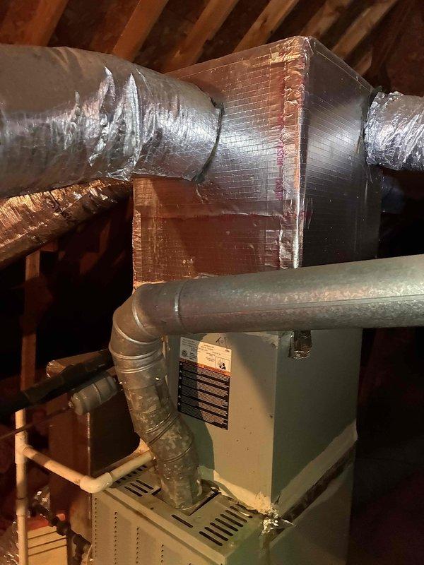 Responded to service call for HVAC system leaking in attic space. Upon inspection, identified active leak at evaporator coil assembly located within Trane XE 80 furnace unit. Opened top access panel and examined A-coil configuration, checking for clogged condensate drain line, damaged drain pan, and coil freeze conditions. Inspected condensate drainage system including PVC piping and verified proper pitch and flow. Documented equipment condition and leak source with photographs showing furnace interior, coil assembly, ductwork connections, and surrounding attic installation. Assessed both the primary air handler and secondary green-painted HVAC unit for potential cross-contamination or additional moisture issues. Responded to service call for HVAC system leaking in attic space. Upon inspection, identified active leak at evaporator coil assembly located within Trane XE 80 furnace unit. Opened top access panel and examined A-coil configuration, checking for clogged condensate drain line, damaged drain pan, and coil freeze conditions. Inspected condensate drainage system including PVC piping and verified proper pitch and flow. Documented equipment condition and leak source with photographs showing furnace interior, coil assembly, ductwork connections, and surrounding attic installation. Assessed both the primary air handler and secondary green-painted HVAC unit for potential cross-contamination or additional moisture issues.