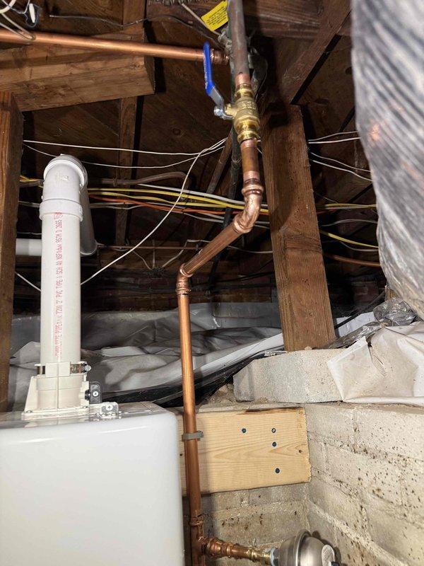 Completed installation of tankless water heater system with new copper supply piping, brass fittings, and shutoff valve in basement crawl space. Installed exterior PVC venting through brick wall with proper termination points above grade near foundation plantings. Completed installation of tankless water heater system with new copper supply piping, brass fittings, and shutoff valve in basement crawl space. Installed exterior PVC venting through brick wall with proper termination points above grade near foundation plantings.