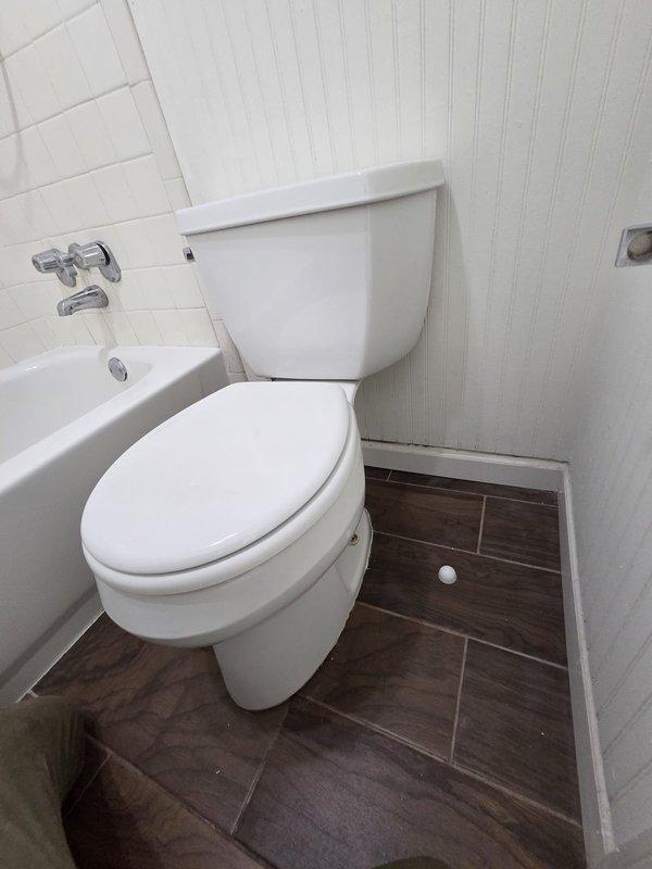 Responded to report of water leak visible through ceiling. Upon arrival, conducted thorough inspection of bathroom directly above affected area. Examined all plumbing fixtures including toilet, bathtub faucet assembly, and visible supply lines. Inspected floor-to-toilet seal, water supply connections, and tub drain assembly for signs of active leakage or moisture. Documented bathroom condition with photographs showing toilet installation, tub fixtures with chrome cross-handle faucets, subway tile surround, and wood-look tile flooring. No active leak observed during inspection period. Recommended monitoring for recurrence and further investigation if leak reappears. Responded to report of water leak visible through ceiling. Upon arrival, conducted thorough inspection of bathroom directly above affected area. Examined all plumbing fixtures including toilet, bathtub faucet assembly, and visible supply lines. Inspected floor-to-toilet seal, water supply connections, and tub drain assembly for signs of active leakage or moisture. Documented bathroom condition with photographs showing toilet installation, tub fixtures with chrome cross-handle faucets, subway tile surround, and wood-look tile flooring. No active leak observed during inspection period. Recommended monitoring for recurrence and further investigation if leak reappears.