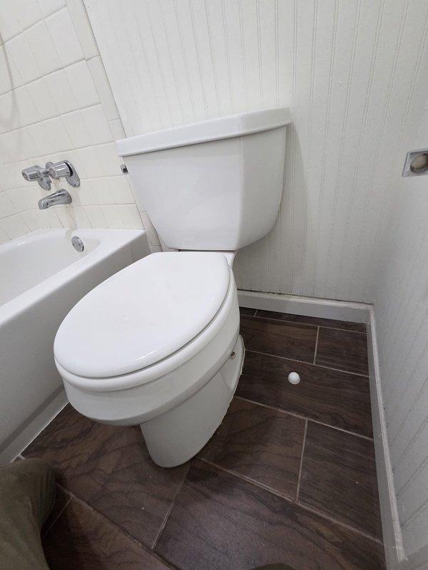 Responded to report of water leak visible through ceiling. Upon arrival, conducted thorough inspection of bathroom directly above affected area. Examined all plumbing fixtures including toilet, bathtub faucet assembly, and visible supply lines. Inspected floor-to-toilet seal, water supply connections, and tub drain assembly for signs of active leakage or moisture. Documented bathroom condition with photographs showing toilet installation, tub fixtures with chrome cross-handle faucets, subway tile surround, and wood-look tile flooring. No active leak observed during inspection period. Recommended monitoring for recurrence and further investigation if leak reappears. Responded to report of water leak visible through ceiling. Upon arrival, conducted thorough inspection of bathroom directly above affected area. Examined all plumbing fixtures including toilet, bathtub faucet assembly, and visible supply lines. Inspected floor-to-toilet seal, water supply connections, and tub drain assembly for signs of active leakage or moisture. Documented bathroom condition with photographs showing toilet installation, tub fixtures with chrome cross-handle faucets, subway tile surround, and wood-look tile flooring. No active leak observed during inspection period. Recommended monitoring for recurrence and further investigation if leak reappears.