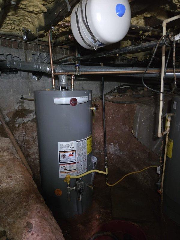 Responded to service call for leaking 40-gallon gas water heater installed in 2017. Upon inspection, confirmed active leak at bottom of tank indicating internal tank failure. Documented existing dual water heater installation with overhead expansion tank and copper supply lines. Photographed equipment condition and surrounding mechanical systems to provide estimate for water heater replacement. Responded to service call for leaking 40-gallon gas water heater installed in 2017. Upon inspection, confirmed active leak at bottom of tank indicating internal tank failure. Documented existing dual water heater installation with overhead expansion tank and copper supply lines. Photographed equipment condition and surrounding mechanical systems to provide estimate for water heater replacement.