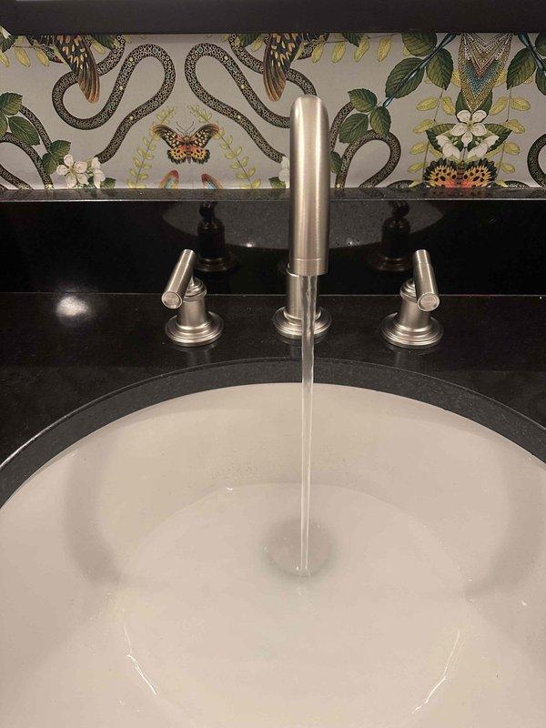 Completed faucet replacement in bathroom sink with widespread three-piece brushed nickel fixture featuring two separate handles and central spout. Installed new drain assembly with P-trap configuration and connected braided metal supply lines to ensure proper water flow and drainage functionality. Completed faucet replacement in bathroom sink with widespread three-piece brushed nickel fixture featuring two separate handles and central spout. Installed new drain assembly with P-trap configuration and connected braided metal supply lines to ensure proper water flow and drainage functionality.