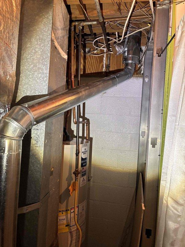 # HVAC Vent Pipe Assessment
Conducted on-site evaluation of existing HVAC exhaust venting system in residential basement mechanical room. Inspected current single-wall metal ductwork configuration connected to furnace unit. Assessed installation routing, clearances from combustible materials, and compliance requirements for proper venting. Documented existing conditions including galvanized metal duct with elbow joint, connection points at air handler unit, and proximity to building structure and insulation materials. Evaluated space constraints and accessibility for potential conversion to double-wall vent pipe system. Photographed current installation showing ductwork path, equipment layout, copper piping, water heater location, and mechanical room configuration to support estimate preparation for upgrading to code-compliant double-wall venting. # HVAC Vent Pipe Assessment
Conducted on-site evaluation of existing HVAC exhaust venting system in residential basement mechanical room. Inspected current single-wall metal ductwork configuration connected to furnace unit. Assessed installation routing, clearances from combustible materials, and compliance requirements for proper venting. Documented existing conditions including galvanized metal duct with elbow joint, connection points at air handler unit, and proximity to building structure and insulation materials. Evaluated space constraints and accessibility for potential conversion to double-wall vent pipe system. Photographed current installation showing ductwork path, equipment layout, copper piping, water heater location, and mechanical room configuration to support estimate preparation for upgrading to code-compliant double-wall venting.