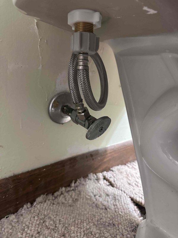 Responded to customer complaint of toilet tank refilling slowly. Upon inspection, found toilet fill valve operating at reduced flow rate. Examined tank interior and noted mineral buildup on internal components and porcelain surfaces. Inspected water supply line and angle stop valve beneath fixture for flow restrictions. Verified braided supply line and chrome shut-off valve were in good condition with no visible kinks or obstructions. Diagnosed slow fill issue as likely caused by debris or mineral deposits restricting flow through fill valve. Documented tank conditions including low water level, sediment accumulation, and discolored porcelain from hard water deposits. Photographed flush mechanism components including metal fill valve assembly, black plastic flush valve with red flapper, and overflow tube for service records. Responded to customer complaint of toilet tank refilling slowly. Upon inspection, found toilet fill valve operating at reduced flow rate. Examined tank interior and noted mineral buildup on internal components and porcelain surfaces. Inspected water supply line and angle stop valve beneath fixture for flow restrictions. Verified braided supply line and chrome shut-off valve were in good condition with no visible kinks or obstructions. Diagnosed slow fill issue as likely caused by debris or mineral deposits restricting flow through fill valve. Documented tank conditions including low water level, sediment accumulation, and discolored porcelain from hard water deposits. Photographed flush mechanism components including metal fill valve assembly, black plastic flush valve with red flapper, and overflow tube for service records.