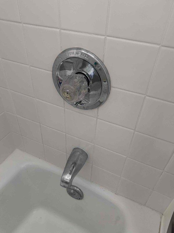 # Leak Repair - Bathtub Temperature Control Valve
Responded to service call for leaking temperature control valve on bathtub fixture. Upon inspection, identified leak originating from single-handle shower/tub control valve assembly mounted on tiled wall above tub spout. Valve escutcheon plate showed signs of age with visible discoloration and worn finish around mounting area. Handle components were partially disassembled to access internal valve mechanism. Diagnosed worn cartridge seals as source of leak. Replaced faulty valve cartridge, installed new seals, and reassembled handle assembly with proper torque specifications. Tested fixture operation through multiple temperature adjustments and verified no leaks present at valve body or escutcheon interface. System restored to full functionality with proper temperature control and water flow. # Leak Repair - Bathtub Temperature Control Valve
Responded to service call for leaking temperature control valve on bathtub fixture. Upon inspection, identified leak originating from single-handle shower/tub control valve assembly mounted on tiled wall above tub spout. Valve escutcheon plate showed signs of age with visible discoloration and worn finish around mounting area. Handle components were partially disassembled to access internal valve mechanism. Diagnosed worn cartridge seals as source of leak. Replaced faulty valve cartridge, installed new seals, and reassembled handle assembly with proper torque specifications. Tested fixture operation through multiple temperature adjustments and verified no leaks present at valve body or escutcheon interface. System restored to full functionality with proper temperature control and water flow.