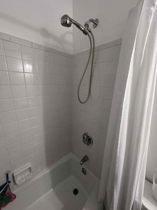 # Leak Repair - Bathtub Temperature Control Valve
Responded to service call for leaking temperature control valve on bathtub fixture. Upon inspection, identified leak originating from single-handle shower/tub control valve assembly mounted on tiled wall above tub spout. Valve escutcheon plate showed signs of age with visible discoloration and worn finish around mounting area. Handle components were partially disassembled to access internal valve mechanism. Diagnosed worn cartridge seals as source of leak. Replaced faulty valve cartridge, installed new seals, and reassembled handle assembly with proper torque specifications. Tested fixture operation through multiple temperature adjustments and verified no leaks present at valve body or escutcheon interface. System restored to full functionality with proper temperature control and water flow. # Leak Repair - Bathtub Temperature Control Valve
Responded to service call for leaking temperature control valve on bathtub fixture. Upon inspection, identified leak originating from single-handle shower/tub control valve assembly mounted on tiled wall above tub spout. Valve escutcheon plate showed signs of age with visible discoloration and worn finish around mounting area. Handle components were partially disassembled to access internal valve mechanism. Diagnosed worn cartridge seals as source of leak. Replaced faulty valve cartridge, installed new seals, and reassembled handle assembly with proper torque specifications. Tested fixture operation through multiple temperature adjustments and verified no leaks present at valve body or escutcheon interface. System restored to full functionality with proper temperature control and water flow.