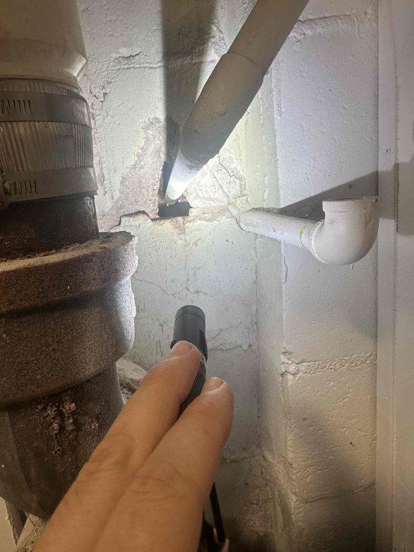 Responded to customer report of water leak in basement beneath main bathroom area. Conducted thorough inspection of confined utility space, examining plumbing connections, drainage systems, and HVAC ductwork in vicinity of reported leak. Utilized flashlight to inspect wall-to-floor junctions, PVC drainage piping, and mechanical components for signs of active water intrusion or moisture damage. Observed cracking in wall surfaces and previous water staining on concrete floor.
Inspected sump pump system as requested, examining dual vertical discharge pipes, mounting straps, electronic sensor components, and pump basin cover. Noted extensive historical water staining and discoloration on concrete floor surrounding sump pump installation, indicating past moisture events. Evaluated overall condition of sump pump assembly and drainage configuration. Documented findings with photographic evidence of inspection areas for customer records. Responded to customer report of water leak in basement beneath main bathroom area. Conducted thorough inspection of confined utility space, examining plumbing connections, drainage systems, and HVAC ductwork in vicinity of reported leak. Utilized flashlight to inspect wall-to-floor junctions, PVC drainage piping, and mechanical components for signs of active water intrusion or moisture damage. Observed cracking in wall surfaces and previous water staining on concrete floor.
Inspected sump pump system as requested, examining dual vertical discharge pipes, mounting straps, electronic sensor components, and pump basin cover. Noted extensive historical water staining and discoloration on concrete floor surrounding sump pump installation, indicating past moisture events. Evaluated overall condition of sump pump assembly and drainage configuration. Documented findings with photographic evidence of inspection areas for customer records.