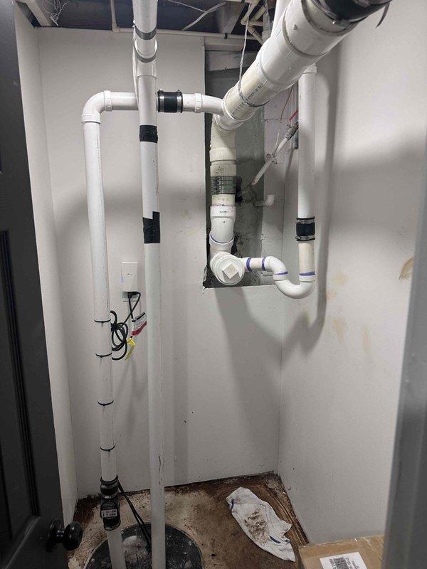 Completed installation and repair of exterior cleanout system. Excavated trench in clay soil and installed white PVC cleanout pipe with proper fittings and connections, ensuring adequate base support with stone material. Extended piping system into interior mechanical room with new vertical and horizontal PVC runs, utilizing black couplings and elbow joints to integrate with existing plumbing infrastructure. Completed installation and repair of exterior cleanout system. Excavated trench in clay soil and installed white PVC cleanout pipe with proper fittings and connections, ensuring adequate base support with stone material. Extended piping system into interior mechanical room with new vertical and horizontal PVC runs, utilizing black couplings and elbow joints to integrate with existing plumbing infrastructure.