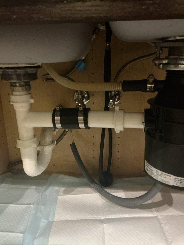Responded to customer report of leak under kitchen sink and dishwasher drainage issue. Upon inspection, identified compromised connections in the P-trap assembly and dishwasher drain hose attachment points. The corrugated dishwasher drain line showed signs of improper sealing at the connection point to the disposal unit. Tightened all hose clamps and verified proper alignment of the P-trap configuration. Checked garbage disposal connections and ensured all PVC fittings were secure. Placed absorbent material under sink to monitor for any residual leakage. Tested system by running water through sink and operating dishwasher drain cycle to confirm proper drainage and verify leak resolution. Responded to customer report of leak under kitchen sink and dishwasher drainage issue. Upon inspection, identified compromised connections in the P-trap assembly and dishwasher drain hose attachment points. The corrugated dishwasher drain line showed signs of improper sealing at the connection point to the disposal unit. Tightened all hose clamps and verified proper alignment of the P-trap configuration. Checked garbage disposal connections and ensured all PVC fittings were secure. Placed absorbent material under sink to monitor for any residual leakage. Tested system by running water through sink and operating dishwasher drain cycle to confirm proper drainage and verify leak resolution.