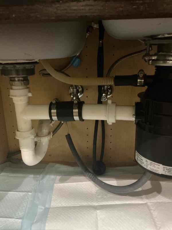 Responded to customer report of leak under kitchen sink and dishwasher drainage issue. Upon inspection, identified compromised connections in the P-trap assembly and dishwasher drain hose attachment points. The corrugated dishwasher drain line showed signs of improper sealing at the connection point to the disposal unit. Tightened all hose clamps and verified proper alignment of the P-trap configuration. Checked garbage disposal connections and ensured all PVC fittings were secure. Placed absorbent material under sink to monitor for any residual leakage. Tested system by running water through sink and operating dishwasher drain cycle to confirm proper drainage and verify leak resolution. Responded to customer report of leak under kitchen sink and dishwasher drainage issue. Upon inspection, identified compromised connections in the P-trap assembly and dishwasher drain hose attachment points. The corrugated dishwasher drain line showed signs of improper sealing at the connection point to the disposal unit. Tightened all hose clamps and verified proper alignment of the P-trap configuration. Checked garbage disposal connections and ensured all PVC fittings were secure. Placed absorbent material under sink to monitor for any residual leakage. Tested system by running water through sink and operating dishwasher drain cycle to confirm proper drainage and verify leak resolution.