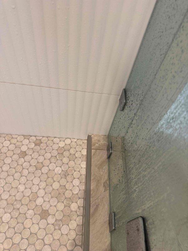 Responded to leak investigation following shower replacement by remediation company. Accessed ceiling cavity to inspect drain-side plumbing connections and identified source of water intrusion. Created access point in ceiling to examine joists and plumbing infrastructure, documented conditions with photos showing shower area with newly installed fixtures and hexagonal tile flooring, and assessed drainage system integrity to determine cause of ceiling leak. Responded to leak investigation following shower replacement by remediation company. Accessed ceiling cavity to inspect drain-side plumbing connections and identified source of water intrusion. Created access point in ceiling to examine joists and plumbing infrastructure, documented conditions with photos showing shower area with newly installed fixtures and hexagonal tile flooring, and assessed drainage system integrity to determine cause of ceiling leak.