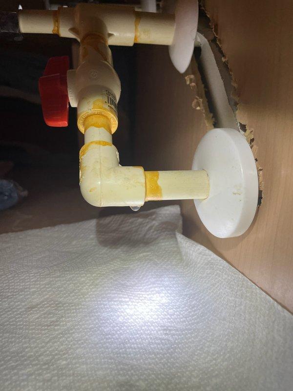 Responded to customer report of leak beneath bathroom vanity. Upon inspection, identified leak originating from P-trap assembly connections. Disassembled existing white PVC P-trap configuration, including horizontal drain line, elbow joint, and vertical trap section. Applied fresh yellow PTFE thread sealant tape to all threaded connections to ensure proper seal. Reassembled P-trap components with proper alignment and hand-tightened all joints. Verified wall flange escutcheon plate was properly seated where drain pipe enters wall. Tested system by running water through drain and confirmed all connections were leak-free with no visible water seepage. Left work area clean and operational. Responded to customer report of leak beneath bathroom vanity. Upon inspection, identified leak originating from P-trap assembly connections. Disassembled existing white PVC P-trap configuration, including horizontal drain line, elbow joint, and vertical trap section. Applied fresh yellow PTFE thread sealant tape to all threaded connections to ensure proper seal. Reassembled P-trap components with proper alignment and hand-tightened all joints. Verified wall flange escutcheon plate was properly seated where drain pipe enters wall. Tested system by running water through drain and confirmed all connections were leak-free with no visible water seepage. Left work area clean and operational.