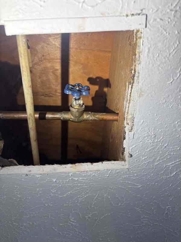 Responded to leaking valve serving outdoor hose bibb in Unit H-1. Created wall access opening to expose faulty valve assembly on copper water supply line. Replaced defective valve with new brass shut-off valve featuring quarter-turn ball valve mechanism with blue handle for positive shut-off control. Tested system under pressure to verify complete seal and proper operation. Access opening left for HOA-approved completion of drywall repair and finish work. Responded to leaking valve serving outdoor hose bibb in Unit H-1. Created wall access opening to expose faulty valve assembly on copper water supply line. Replaced defective valve with new brass shut-off valve featuring quarter-turn ball valve mechanism with blue handle for positive shut-off control. Tested system under pressure to verify complete seal and proper operation. Access opening left for HOA-approved completion of drywall repair and finish work.