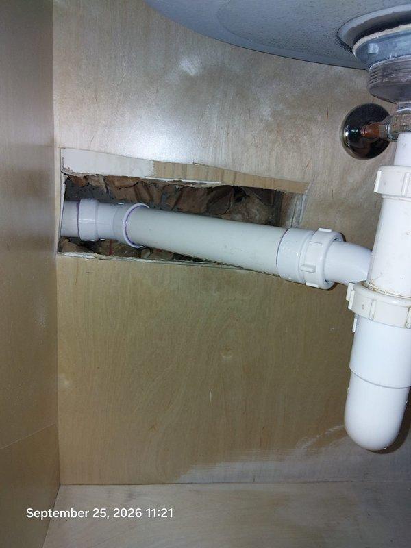 Completed drain replacement in bathroom vanity cabinet and adjacent wall access area. Removed and replaced deteriorated PVC drain pipe and P-trap assembly showing water damage and age-related wear. Accessed plumbing system through existing cabinet opening and wall cavity, working around copper supply lines, black waste stack, and electrical components. Successfully installed new white PVC drainage components, ensuring proper trap configuration and secure connections to prevent future leaks and sewer gas infiltration. Completed drain replacement in bathroom vanity cabinet and adjacent wall access area. Removed and replaced deteriorated PVC drain pipe and P-trap assembly showing water damage and age-related wear. Accessed plumbing system through existing cabinet opening and wall cavity, working around copper supply lines, black waste stack, and electrical components. Successfully installed new white PVC drainage components, ensuring proper trap configuration and secure connections to prevent future leaks and sewer gas infiltration.
