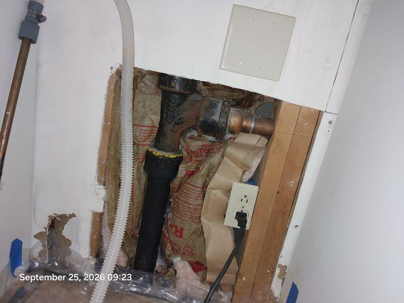 Completed drain replacement in bathroom vanity cabinet and adjacent wall access area. Removed and replaced deteriorated PVC drain pipe and P-trap assembly showing water damage and age-related wear. Accessed plumbing system through existing cabinet opening and wall cavity, working around copper supply lines, black waste stack, and electrical components. Successfully installed new white PVC drainage components, ensuring proper trap configuration and secure connections to prevent future leaks and sewer gas infiltration. Completed drain replacement in bathroom vanity cabinet and adjacent wall access area. Removed and replaced deteriorated PVC drain pipe and P-trap assembly showing water damage and age-related wear. Accessed plumbing system through existing cabinet opening and wall cavity, working around copper supply lines, black waste stack, and electrical components. Successfully installed new white PVC drainage components, ensuring proper trap configuration and secure connections to prevent future leaks and sewer gas infiltration.