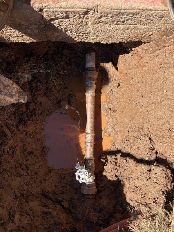 Completed underground water line repair involving excavation and pipe replacement. Exposed and replaced deteriorated galvanized steel piping with new materials, including installation of proper fittings and connections. Excavated trench through multiple soil layers to access the damaged section, removed old piping showing signs of corrosion and age-related deterioration, and installed replacement pipe with white PVC fittings and couplings. Managed standing water accumulation in the trench during repair process. All connections were properly threaded and secured to ensure leak-free operation of the underground water system. Completed underground water line repair involving excavation and pipe replacement. Exposed and replaced deteriorated galvanized steel piping with new materials, including installation of proper fittings and connections. Excavated trench through multiple soil layers to access the damaged section, removed old piping showing signs of corrosion and age-related deterioration, and installed replacement pipe with white PVC fittings and couplings. Managed standing water accumulation in the trench during repair process. All connections were properly threaded and secured to ensure leak-free operation of the underground water system.
