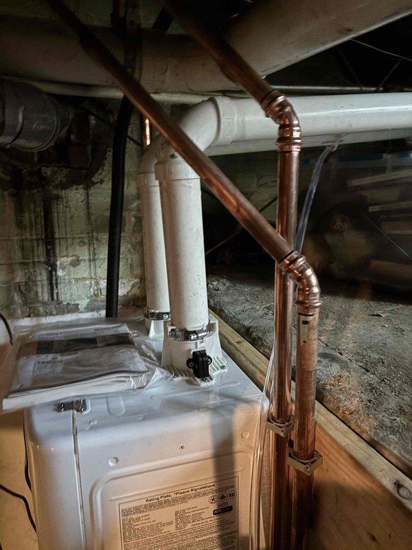 Completed installation of tankless water heater system in basement utility area. Installed and connected copper supply lines with proper fittings and white PVC venting pipe routed through ceiling joists to exterior. Configured condensate pump with drainage piping to handle system discharge. All connections pressure-tested and system commissioned successfully. Completed installation of tankless water heater system in basement utility area. Installed and connected copper supply lines with proper fittings and white PVC venting pipe routed through ceiling joists to exterior. Configured condensate pump with drainage piping to handle system discharge. All connections pressure-tested and system commissioned successfully.