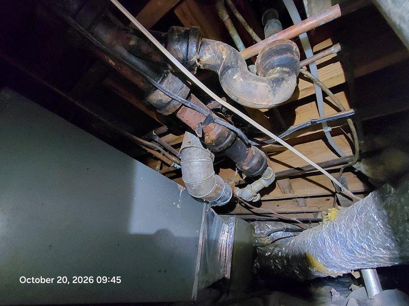 Inspected the drain, waste, and vent system in response to a sewer odor complaint and found severely corroded cast iron piping and P-trap with heavy rust scaling and deteriorated banded couplings in the crawlspace, a likely source of sewer gas intrusion. A torn vapor barrier with moisture staining was also observed near the drain assembly. Documented conditions with photos and recommend replacing the deteriorated cast iron sections and repairing the vapor barrier to eliminate the odor and prevent further leakage. Inspected the drain, waste, and vent system in response to a sewer odor complaint and found severely corroded cast iron piping and P-trap with heavy rust scaling and deteriorated banded couplings in the crawlspace, a likely source of sewer gas intrusion. A torn vapor barrier with moisture staining was also observed near the drain assembly. Documented conditions with photos and recommend replacing the deteriorated cast iron sections and repairing the vapor barrier to eliminate the odor and prevent further leakage.