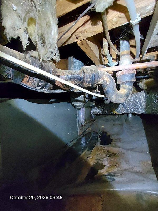 Inspected the drain, waste, and vent system in response to a sewer odor complaint and found severely corroded cast iron piping and P-trap with heavy rust scaling and deteriorated banded couplings in the crawlspace, a likely source of sewer gas intrusion. A torn vapor barrier with moisture staining was also observed near the drain assembly. Documented conditions with photos and recommend replacing the deteriorated cast iron sections and repairing the vapor barrier to eliminate the odor and prevent further leakage. Inspected the drain, waste, and vent system in response to a sewer odor complaint and found severely corroded cast iron piping and P-trap with heavy rust scaling and deteriorated banded couplings in the crawlspace, a likely source of sewer gas intrusion. A torn vapor barrier with moisture staining was also observed near the drain assembly. Documented conditions with photos and recommend replacing the deteriorated cast iron sections and repairing the vapor barrier to eliminate the odor and prevent further leakage.