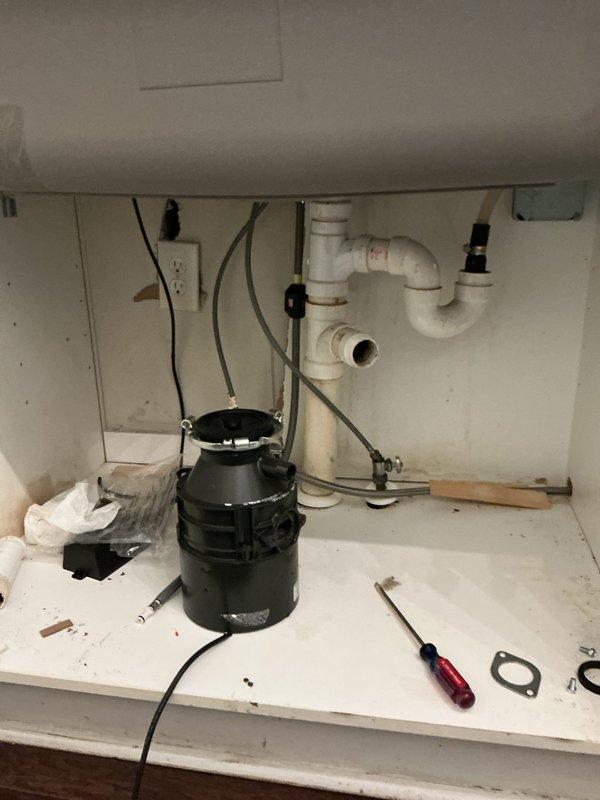 Inspected the under-sink cabinet to assess existing drain and supply configurations for a kitchen remodel with a new sink, documenting the PVC drain assembly with P-trap, capped drain stub-out, braided supply lines, garbage disposal, and electrical connections requiring modification. Performed a pressure test on the plumbing system with a gauge, recording approximately 50–60 psi, to verify supply line integrity prior to re-piping to accommodate the new sink. Inspected the under-sink cabinet to assess existing drain and supply configurations for a kitchen remodel with a new sink, documenting the PVC drain assembly with P-trap, capped drain stub-out, braided supply lines, garbage disposal, and electrical connections requiring modification. Performed a pressure test on the plumbing system with a gauge, recording approximately 50–60 psi, to verify supply line integrity prior to re-piping to accommodate the new sink.