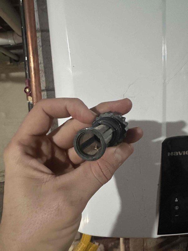Inspected the Navien tankless water heater in response to a flush request and removed the inlet cold water filter screen, which was heavily clogged with dark sediment and debris, restricting flow. The filter was cleaned and inspected for reassembly, and the unit's gas line, drain, and supply piping were observed to be in place. A flush of the heat exchanger with descaling solution is recommended to restore full performance and efficiency. Inspected the Navien tankless water heater in response to a flush request and removed the inlet cold water filter screen, which was heavily clogged with dark sediment and debris, restricting flow. The filter was cleaned and inspected for reassembly, and the unit's gas line, drain, and supply piping were observed to be in place. A flush of the heat exchanger with descaling solution is recommended to restore full performance and efficiency.