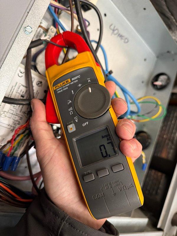 Completed annual heating maintenance on geothermal system. Measured loop temperature at 55.6°F using UEi thermometer at valve connection points, confirming proper operating range. Electrical diagnostics with Fluke 902FC clamp meter showed compressor drawing 0.1 amps at idle, indicating normal electrical function. System is operating within manufacturer specifications for the heating season.