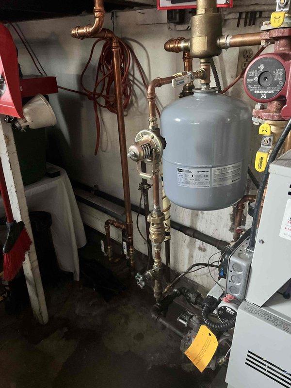 Successfully installed new backflow preventer assembly on boiler system with complete copper pipe rerouting. System includes expansion tank, circulation pump, and proper valve configuration to ensure code compliance and optimal system function.