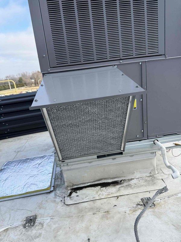 Installed economizer components on rooftop commercial HVAC unit at Americold Logistics facility. System was properly mounted on concrete pad with necessary drainage connections. Confirmed ventilation grilles, access panels and filtration components were in place and functioning as designed.