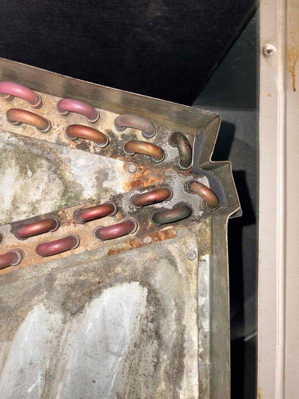 Responded to no-heat call at Mears Machine Corp where maintenance reported furnace not working and leaking condensation. Visual inspection revealed significant corrosion and deterioration on the heat exchanger coils with substantial rust, scale buildup, and mineral deposits. Copper tubes showed oxidation damage consistent with prolonged condensation exposure, confirming maintenance's initial assessment.