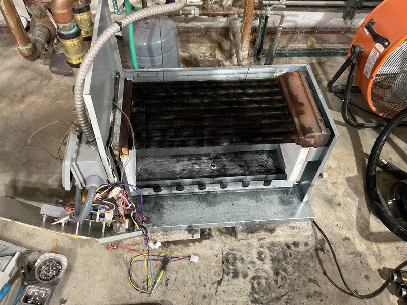 Performed maintenance service on commercial boiler system, disassembling unit to access severely corroded heat exchanger. Cleaned heat exchanger components which showed significant rust formation and soot buildup throughout the coil assembly and burner tubes, documenting condition with photos for service record.
