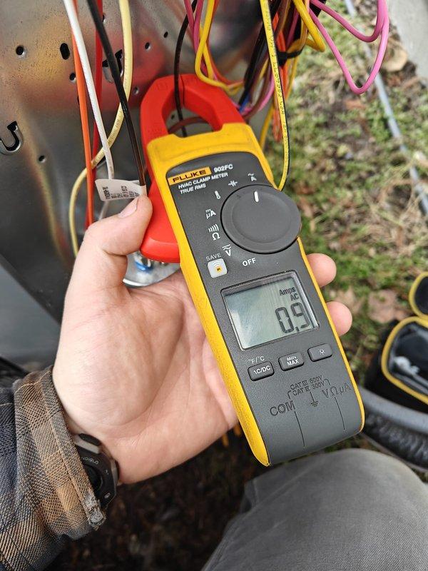 Performed annual heating maintenance service on residential system. Conducted electrical testing with Fluke clamp meter, measuring current draw at 0.9 amps. Inspected outdoor unit fan grill for proper condition and airflow, confirming no obstructions or damage to protective cover.
