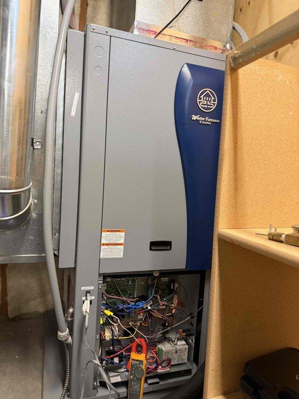 Responded to service call for WaterFurnace system displaying E5 predetect Fp1 error code, which was a recurring issue from two weeks prior. Performed electrical diagnostics using Fluke 902FC clamp meter, measuring amperage and inspecting internal wiring connections. Accessed and examined system components through the bottom panel, focusing on electrical circuits and control board functionality.