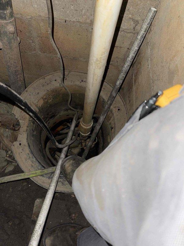 Inspected customer's crawlspace where flooding had occurred, affecting the furnace installed earlier this year. Examined the condensate drain line configuration in the sump pit and surrounding utility area, documenting visible water damage. Customer claims damage resulted from improper condensate line installation leading to water accumulation.