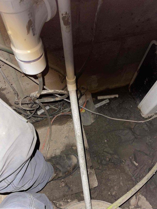 Inspected customer's crawlspace where flooding had occurred, affecting the furnace installed earlier this year. Examined the condensate drain line configuration in the sump pit and surrounding utility area, documenting visible water damage. Customer claims damage resulted from improper condensate line installation leading to water accumulation.