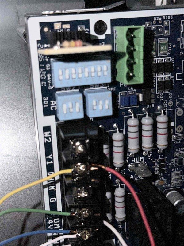 Performed repair service on HVAC control system by inspecting and servicing the electronic circuit board. Identified and addressed issues with the terminal connections, checking multiple colored wires (yellow, green, blue, red, white, and orange) connected to terminal blocks. Verified proper configuration of DIP switches on the control board and confirmed system functionality after repair.