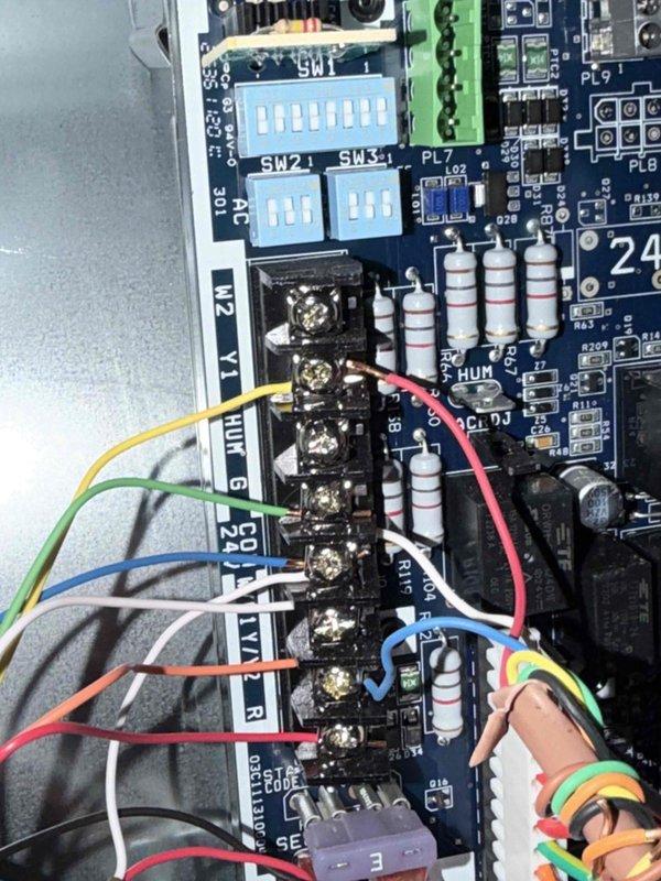 Performed repair service on HVAC control system by inspecting and servicing the electronic circuit board. Identified and addressed issues with the terminal connections, checking multiple colored wires (yellow, green, blue, red, white, and orange) connected to terminal blocks. Verified proper configuration of DIP switches on the control board and confirmed system functionality after repair.