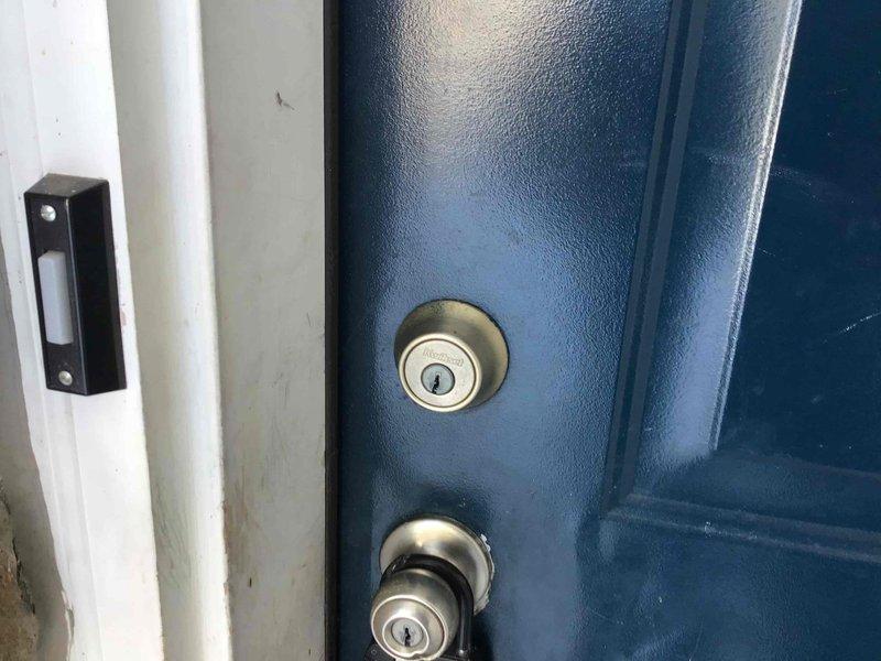 Conducted inspection of residential HVAC system during winter conditions. Observed outdoor heat pump/condenser unit with vegetation entanglement on coil grille and snow accumulation around unit. Noted proper functioning of home entry security components including door sensor mounted on frame adjacent to locking mechanisms.