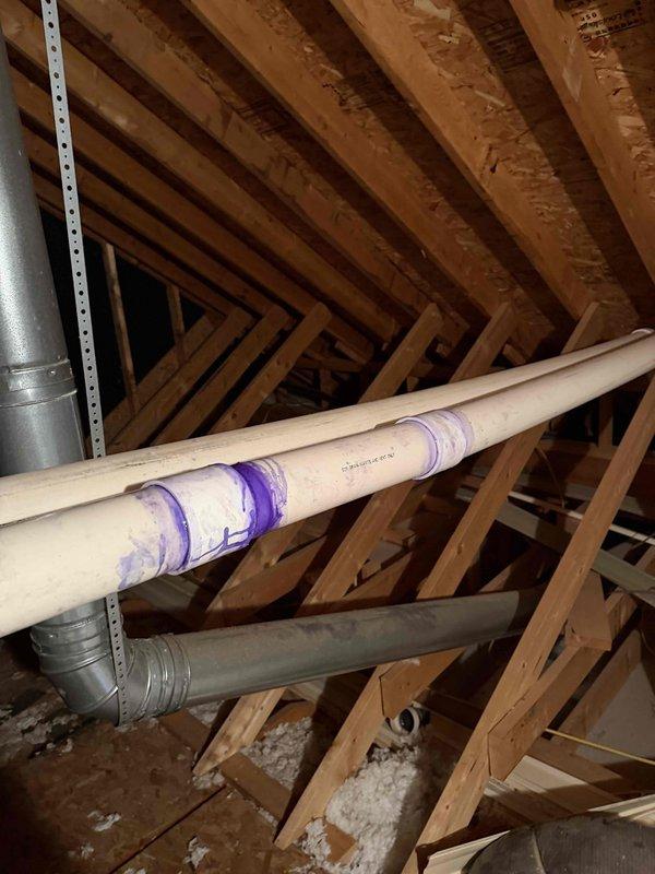 Inspected attic space to assess reported exhaust concerns, observing both the PVC plumbing system and HVAC ductwork. Verified condition of flexible duct insulation and metal strapping, confirming proper installation with no visible damage or deterioration to surrounding wooden structural components.