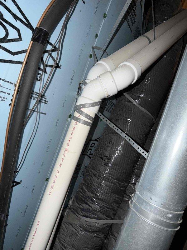 Inspected attic space to assess reported exhaust concerns, observing both the PVC plumbing system and HVAC ductwork. Verified condition of flexible duct insulation and metal strapping, confirming proper installation with no visible damage or deterioration to surrounding wooden structural components.