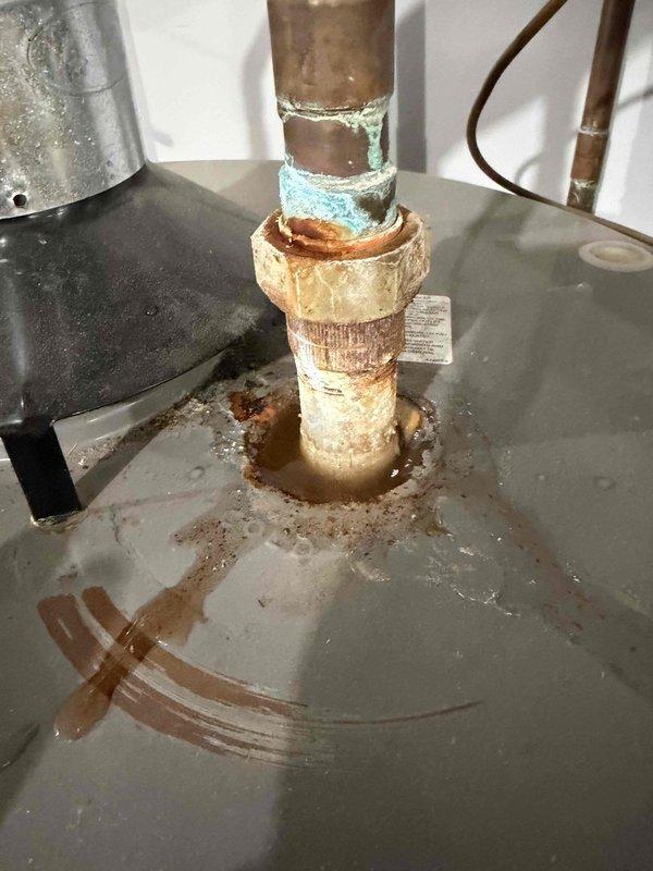 Conducted diagnostic inspection on leaking water heater referred by Ken Shockley. Identified significant corrosion and oxidation on copper pipes with visible turquoise-colored copper oxide formation at connection points. Observed water pooling around base with rust stains indicating ongoing leakage. Noted filter component showing substantial debris buildup requiring maintenance or replacement.